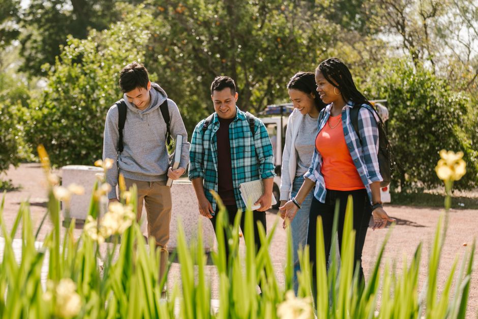 A diverse group of college students walking outdoors, enjoying each other's company and smiling.
